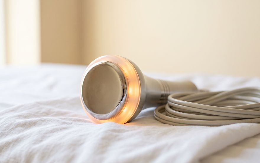 Cabezal de radiofrecuencia con borde ámbar encendido y cable enrollado
